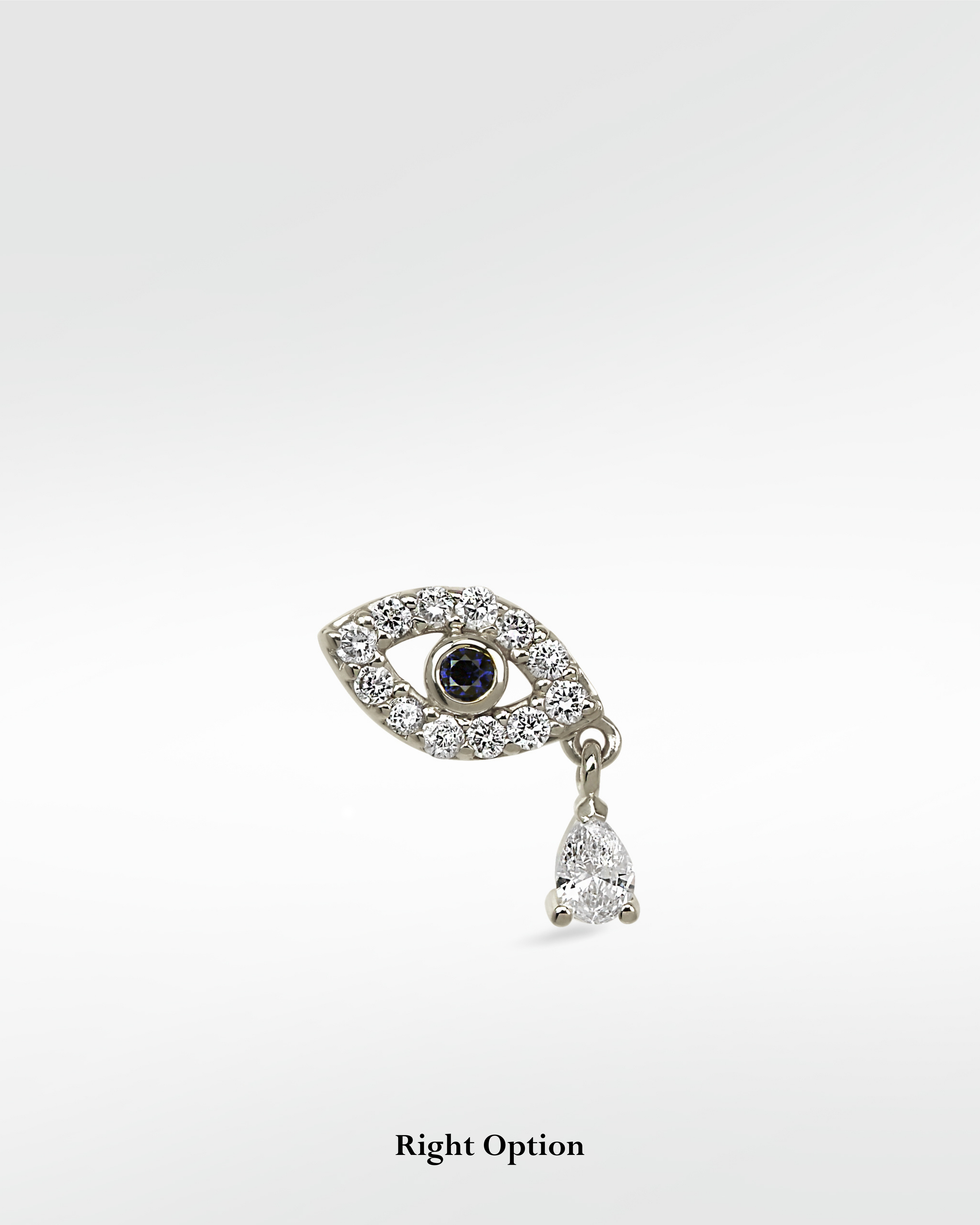 Right option of an evil eye earring in 14k white gold, with a blue sapphire pupil, pavé diamonds, and a dangling pear diamond.