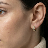 Close-up of a model's ear wearing the 14k gold Modernist Princess Cut Diamond Hoop with channel-set stones.